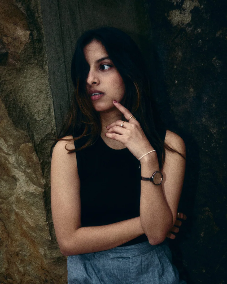 Shrinkhla in a black sleeveless top beside weathered stone