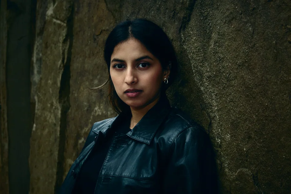 Shrinkhla in a leather jacket against textured stone