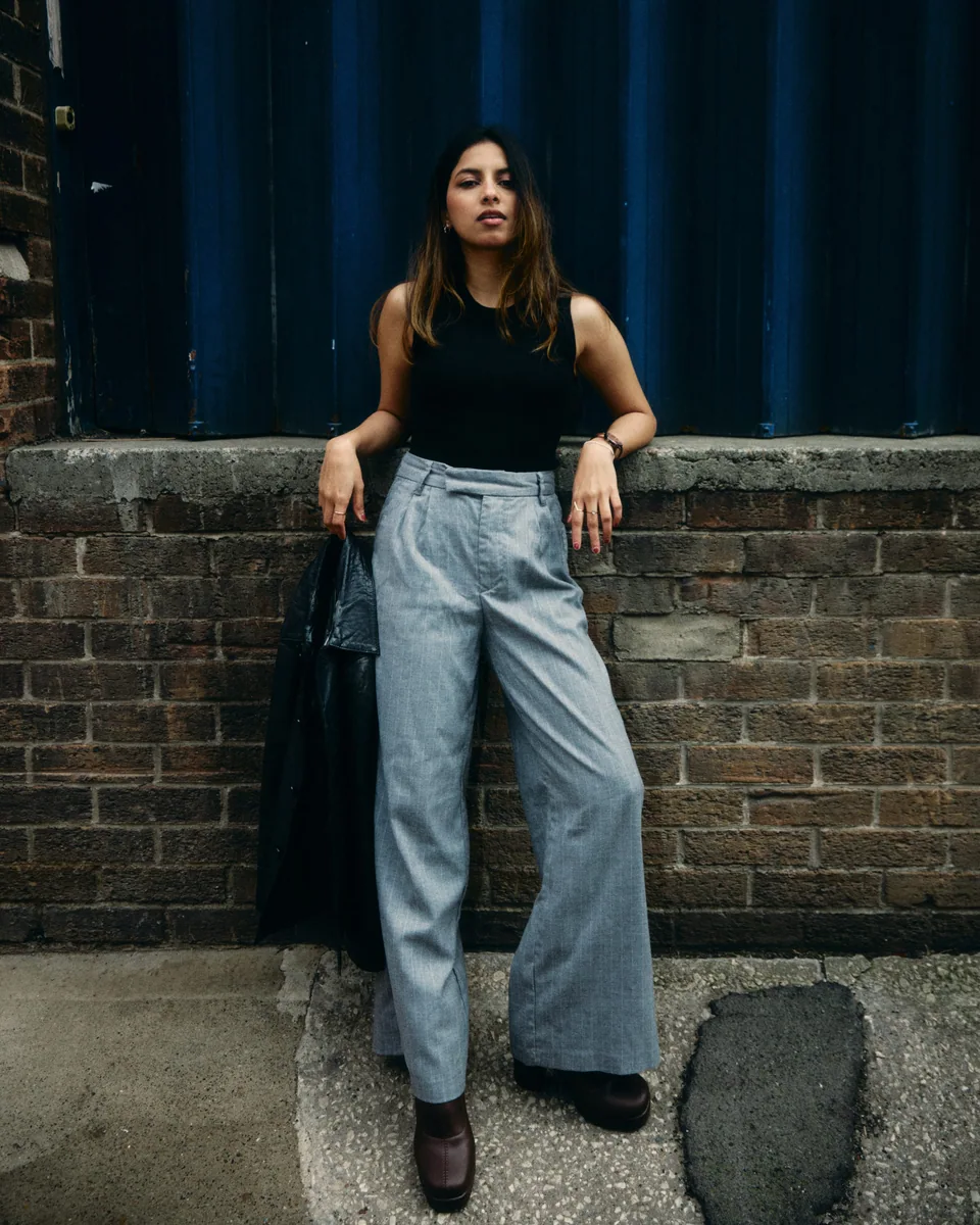 Shrinkhla standing by an urban wall in wide-leg trousers
